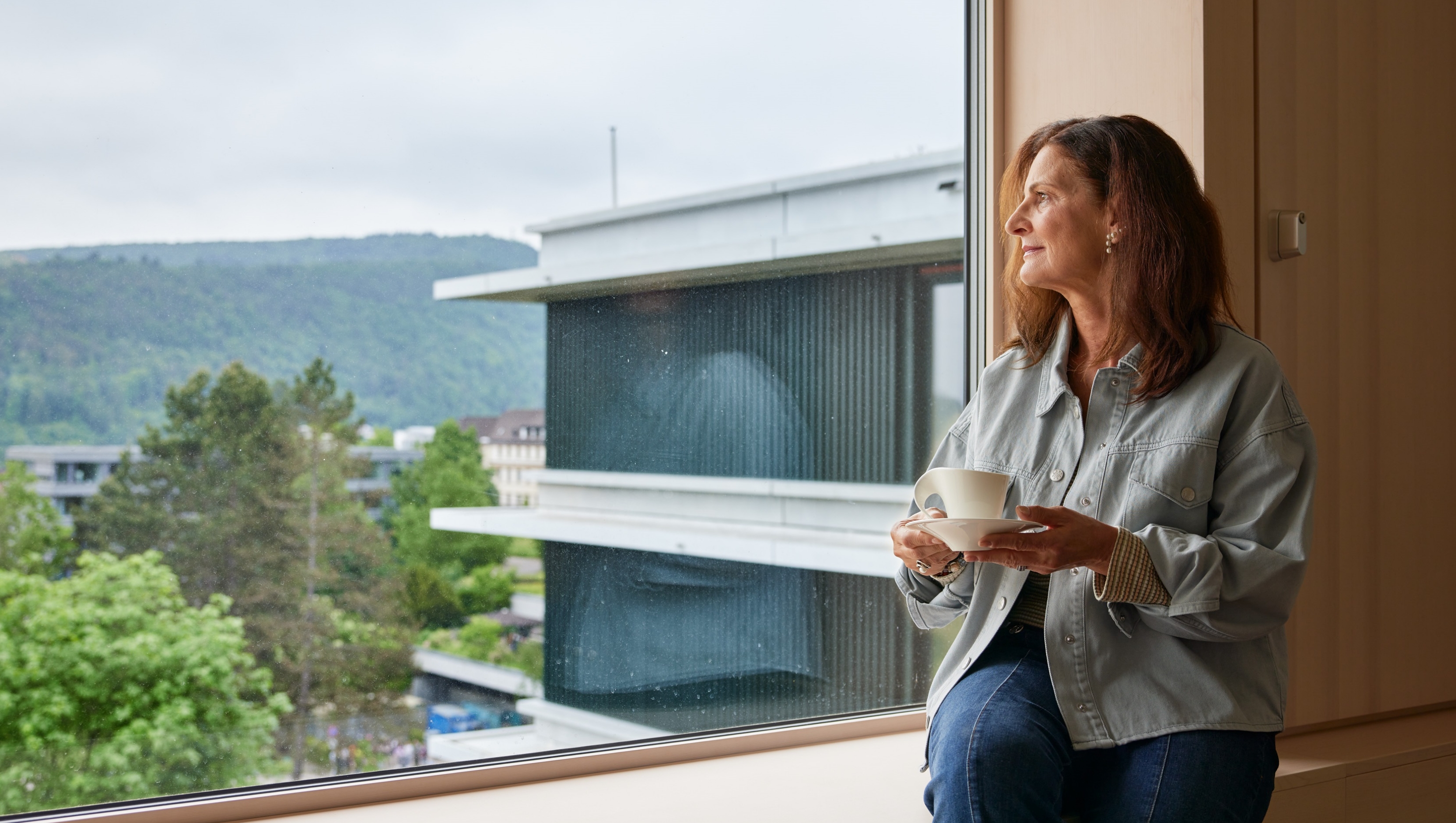 Eine Dame geniesst einen Kaffee auf der Fensterbank